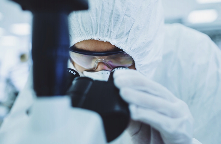 A researcher in the lab peering through a microscope